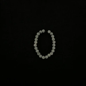 Vitt pärlarmband med marmormönster - Stilrent armband med vita pärlor och grått marmormönster. Elastiskt band gör det enkelt att ta på och av. Perfekt accessoar för att lyfta din outfit.