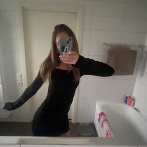 Svart offshoulder klänning - Säljer en svart, tight offshoulder klänning med lång ärm. Klänningen är kort och har en stilren, enkel design som passar perfekt när du vill känna dig extra snygg. Den är helt ny med prislapp kvar.