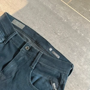 Mörkblå jeans från Replay - Snygga mörkblå jeans från Replay med klassisk femficksdesign och knappgylf. Perfekta för en stilren look. Passar bra till både vardag och mer uppklädda tillfällen.