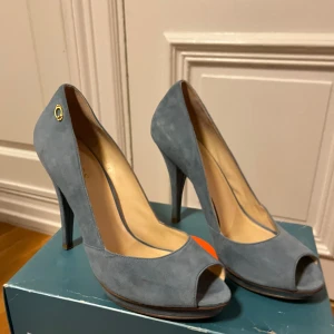 Ljusblå mocka pumps från Guess - Säljer ett par ljusblå pumps i mocka från Guess med öppen tå och hög klack. Använda endast 1 gång, sköna.