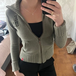 Olivgrön stickad cardigan med dragkedja - Säljer en olivgrön stickad cardigan med dragkedja framtill och hög krage från Esprit. Storlek M men den är väldigt liten i storleken, skulle säga att den passar mer en liten S eller XS. Fint skick! 