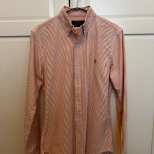 Rosa randig Ralph Lauren skjorta - Väldigt snygg rosa randig Ralph Lauren skjorta! Den är inte använd mycket alls och är i absolut nyskick. Perfekt för en stilren look nu till sommaren. Storlek S slim fit.