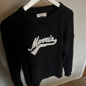 Svart stickad tröja från Morris - Säljer en svart stickad tröja från Morris med en vit broderad logga framtill. Tröjan har en riktigt bra passform och har inga defekter.