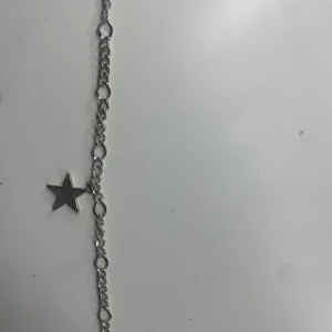 Silverfärgat armband med stjärnhänge - Snyggt armband i silverfärg med en kedja av större länkar och ett hängande stjärnformat berlock. Perfekt för att ge din outfit lite extra edge och stil.💞priset går att diskutera💓