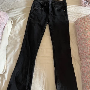 Svarta bootcut jeans - Säljer ett par svarta jeans med bootcut-modell. Byxorna har klassisk femficksdesign, hällor för bälte och stängs med dragkedja och knapp. Perfekta för dig som gillar en tidlös look med lite utsvängda ben.