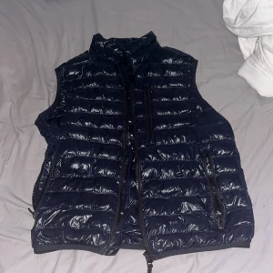 Mörkblå dunväst från Peak Performance - Säljer en mörkblå dunväst från Peak Performance med hög krage och dragkedja framtill. Västen har två sidofickor med dragkedja. Perfekt väst för alla väder. Mvh Vidar 