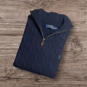 Ralph Lauren Half-Zip Kabelstickad – Marinblå (L) - Ralph Lauren Half-Zip Kabelstickad – Marinblå (L) Säljer en lyxig och stilren half-zip från Ralph Lauren 💼✨ Kabelstickad och i klassisk mörkblå färg 💙 med ikoniska loggan på bröstet 🐎 Perfekt skick – både snygg och bekväm! 	•	Storlek: L 	•	Färg: Marinblå 🔵 	•	Mått: 📏 Längd 70 cm, armhåla till armhåla 55 cm, axel till axel 45 cm 	•	Nypris: 3000+ kr 💸 	•	Snittpris på Vinted: ca 1200 kr 📊  Perfekt för både vardag och fest! Passa på att fynda till ett riktigt bra pris ✅ Finns i Linköping 📍 105