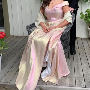 Balklänning - Super fin klänning som skiftar i guld och rosa glitter beroende på vilket ljus man är i. Använd en gång 🩷 Köpt i västerås på Ruths. Storlek 16 men lite insydd