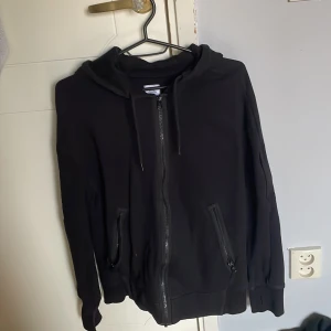 Svart hoodie från C.P. Company - Svart hoodie från C.P. Company som är sparsamt använd och har inga tecken på användning pga växte ur ganska snabbt. Köpt på johnells och nypris låg på 3000kr men har tryck fel i storleken där det står XL men den är egentligen i storlek S ungefär men passar också XS.