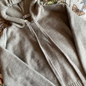 Grå stickad hoodie💕 - Mysig grå stickad hoodie med långa ärmar och ribbade muddar. Tröjan har huva med bred ribbad kant nedtill. Perfekt för kyliga dagar och enkel att matcha med det mesta. Varan visar inga tecken på effekter💕 Skriv vid minsta fundering!
