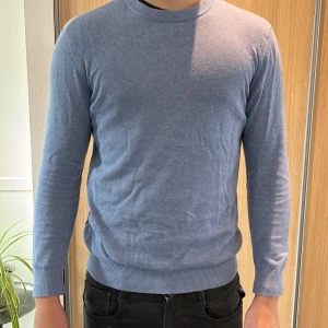 Ljusblå slim fit tröja från H&M - Säljer en ljusblå långärmad tröja från H&M i slim fit-modell. Tröjan har rund halsringning och är tillverkad i ett mjukt material som passar perfekt för lager-på-lager. Enkel och stilren design.