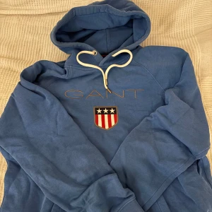 Gant Hoodie - En fin blå Gant Hoodie i fint skick i Storlek: M. Riktigt skön att ha på sig, storleken stämmer överens men jag skulle säga att om du har S så kan man ha den också. Tveka inte på att höra av dig vid frågor och intresse!