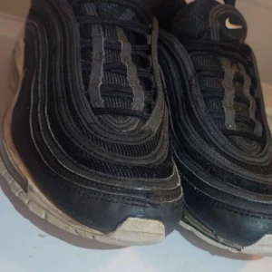 Svarta Nike Air Max sneakers - Svarta Nike Air Max sneakers med ikoniska vågformade detaljer och synlig luftbubbla i sulan. Ovandel i mesh och syntet med vita swoosh-loggor på sidan och tungan. Klassisk snörning och rund tå. Perfekta för dig som gillar streetstyle och sportig vibe.