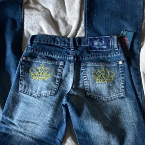 Victoria Beckham bootcutjeans - Snygga blå jeans från Rock & Republic med broderade kronor i gult och strass på bakfickorna. Low waist och bootcut 
