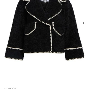Svart teddyjacka från Object - Säljer en svart teddyjacka från Object med kontrasterande vita detaljer längs kanterna. Jackan har stora slag, två fickor framtill och lång ärm. Perfekt för dig som vill ha en trendig och mysig jacka.