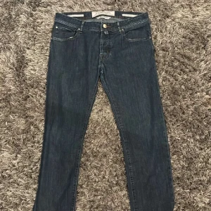 Mörkblå jeans från Jacob Cohen - Snygga mörkblå jeans från Jacob Cohen med klassisk femficksdesign och läderpatch bak i midjan. Jeansen har raka ben och diskreta kontrastsömmar. Perfekta för dig som gillar stilrena och tidlösa jeans med premiumkänsla. Steal för er man kan lätt köpa dem för mer än vad jag säljer dem för.Pris går att diskutera 30- 32/32 nypris 4000.Perfekt för dig som vill Resella eller bara ha ett par feta jeans.tveka inte skicka in prisförslag 