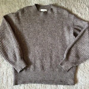 Brun ribbstickad tröja från H&M - Mysig brun ribbstickad tröja från H&M med rund halsringning och långa ärmar. Perfekt för kyligare dagar och enkel att matcha med olika outfits.