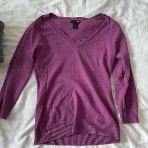 Lila v-ringad tröja från H&M - Säljer en lila v-ringad tröja från H&M i storlek S. Tröjan har långa ärmar, ribbade muddar och nederkant. Perfekt för dig som gillar en enkel men snygg stil. Materialet känns mjukt och passar bra till både jeans och kjol.