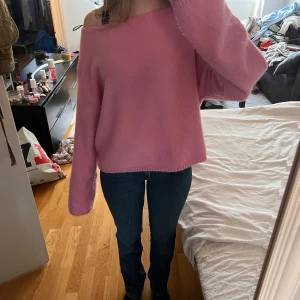 Rosa offshoulder stickad tröja - Säljer en söt rosa stickad tröja med offshoulder-design. Tröjan har lång ärm och en lös, avslappnad passform. 