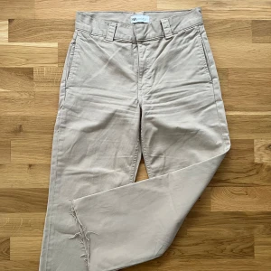 Beige byxor från Zara - Säljer ett par beige byxor från Zara med normal passform och raka ben. Byxorna har råa, fransiga benslut och stängs med dragkedja och hyska. 
