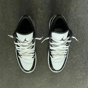 Nike Air Jordans Low svartvita sneakers - Säljer ett par Nike Air Jordans Low i svart och vitt. Skorna har klassisk design med svart swoosh, vit bas och svarta detaljer. De har snörning, rund tå och platt sula. Perfekta för dig som gillar streetwear och vill ha en ikonisk sneaker i garderoben lite smått creased använda en få antal gånger och sko snören behöver tvättas 