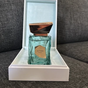 Aether Extrait från French Avenue - Aether Extrait de Parfum från French Avenue, ca 90 ml finns kvar. Flaskan är turkos med geometrisk design och har en lyxig, guldig etikett och lock. Kommer i elegant vit ask med gulddetaljer. Perfekt för dig som gillar exklusiva och snygga parfymer.