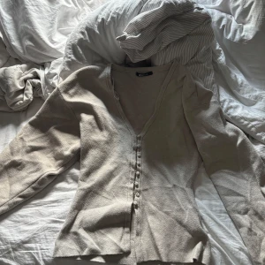 Shaped knitted cardigan  - Supersnygg beige kofta från Gina Tricot med v-ringning och knappar framtill. Långärmad och i mjukt stickat material som sitter skönt på kroppen. Perfekt att slänga över en topp för en chill look. Använd fåtal gånger, nypris 500