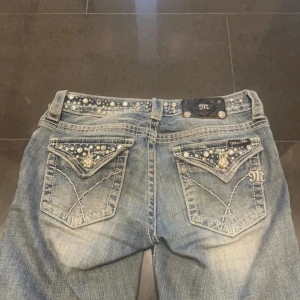 bootcut Miss Me jeans 🪽 - Säljer ett par blå Miss Me jeans med bootcut och snygga pärldetaljer på fickor och linning. Jeansen har dekorativa sömmar och en läderpatch bak med logga. Perfekta för dig som gillar statement-jeans! köpta för 2300💞 pris kan diskuteras vid snabbt köp. dom här jeansen finns på flera sidor (vinted)
