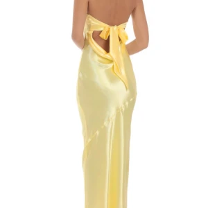 Gul långklänning i satin med rosett - Säljer en elegant gul långklänning i glansig satin med öppen rygg och stor rosett bak. Klänningen har en figurnära passform och axelbandslös design, perfekt för speciella tillfällen som bal.(Oanvänd med prislapp) skriv vid frågor eller om jag ska skicka egna bilder, pris kan diskuteras 💛💛