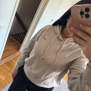 Beige hoodie  - Säljer en beige hoodie  med luva och dragsko. Tröjan har en avslappnad passform och ribbade muddar vid ärmslut och nederkant. Perfekt för en chill och stilren look.