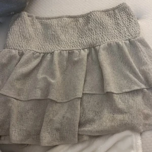 Blå volangkjol med smock - Supersöt blå kjol med bred smock i midjan och dubbla volanger. Kjolen har en luftig och lätt känsla, perfekt för varma dagar. Passar till både sneakers och sandaler. Båda två är helt oanvända då jag kände att dom inte va min stil så vill bli av me båda två 