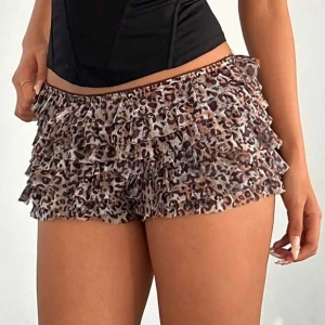 Leopardmönstrade volangshorts - Supersöta shorts med leopardmönster och flera lager volanger. De är lågmidjade och har en loose passform som ger en lekfull vibe. Perfekta för dig som vill sticka ut med ett djurmönster och coola detaljer.