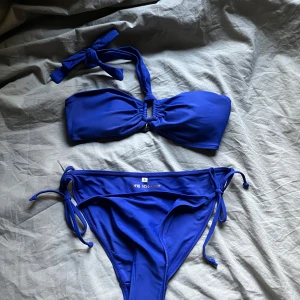 Blå bikini från Sofie Schnoor - Säljer en snygg blå bikini från Sofie Schnoor. Överdelen är bandeau-modell med knyt i nacken och rynkdetalj framtill. Underdelen har lågmidja och knyt i sidorna. Perfekt för stranden eller poolen!