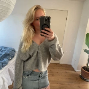 Grå  kofta med v-ringning - Säljer en grå  kofta med v-ringning och långa ärmar. Tröjan är stickad och har en avslappnad passform, perfekt att styla med jeans eller kjol. Supermjuk och skön att ha på sig!