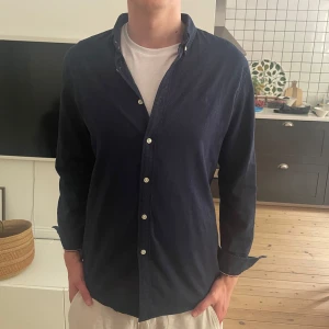 Mörkblå skjorta från polo sport - Snygg mörkblå skjorta från polo sport med små vita prickar och broderad logga på bröstet. Skjortan har klassisk krage, knappar framtill och på ärmsluten. Regular fit för en bekväm passform. Är XXL i barnstorlek men sitter som M!