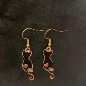 Katter örhängen guld imitation  - Så söta örhängen i form av svarta katter med lång svans. 🐈‍⬛ Ca 2,3 x 0,8 cm. Perfekt för kattälskaren 💕  