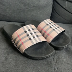 Burberry tofflor - Burberry tofflor i storlek 45, de är lite skadade fast Perfekta tofflor för sommaren och chill dagar. Ikonisk Burberry-look som sticker ut.