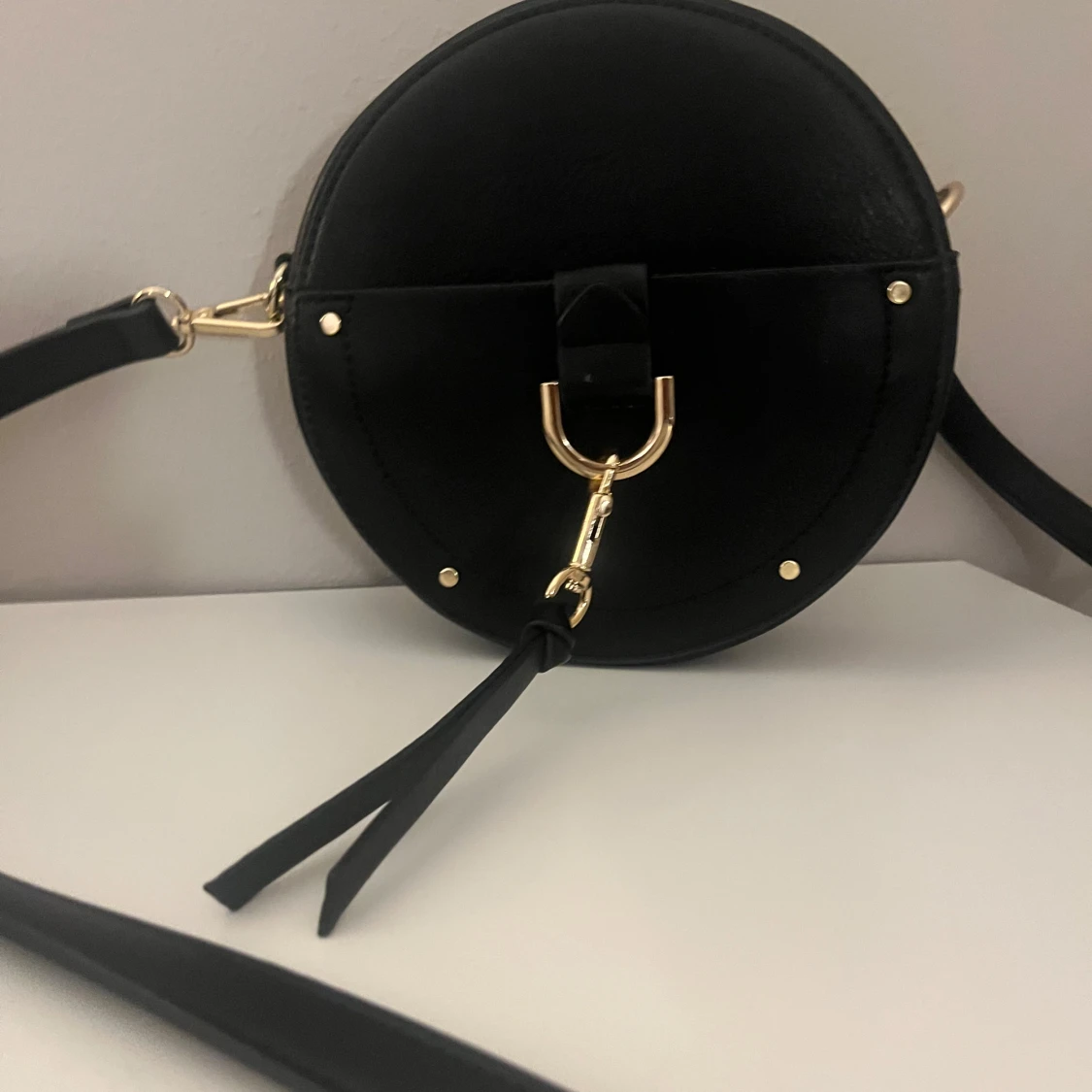 Rund svart axelväska med gulddetaljer