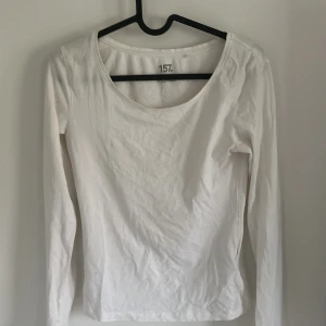 Vit långärmad topp från 157 - Säljer en enkel och stilren vit långärmad topp från 157. Tröjan har rund halsringning och är tillverkad i mjuk bomullsblandning med lite stretch för en bekväm passform. Perfekt basplagg till garderoben!