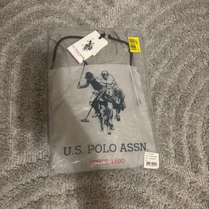 U.S Polo Hoodie - Helt ny oanvänd Polo Hoodie med etikett kvar. Mjuk och bekväm för båda vardag och chill. Grå färg, Polo-logga broderad på bröstet. 