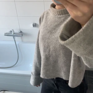 Grå stickad tröja från Gina Tricot - Grå stickad tröja med liten krage och uppvikta armar. Andvänt få gånger men är lite nopprig. Fin och inga fläckar.