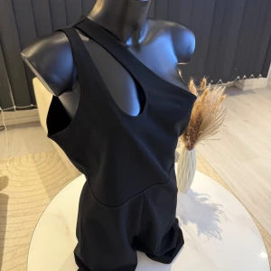 Svart oneshoulder klänning jumpsuit  - Snygg svart oneshoulder klänning med unik design. Perfekt för en kväll ute eller en speciell tillställning. Klänningen har en stilren och modern look. Passar som oversize modell i storlek m/l. Jag rekommenderar den varmt.🌸👌
