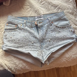 Ljusblå jeansshorts från OneTeaspoon - Snygga ljusblå jeansshorts från OneTeaspoon med pärldetaljer framtill. Shortsen har en klassisk femficksdesign och råa kanter för en avslappnad look. Perfekta för sommardagar! 🌞 säljer eftersom dom är för stora för mig. Kanten har åkt upp/uppklippt. Köpt begagnade