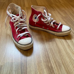 Röda sneakers från Converse - Säljer ett par klassiska röda Converse sneakers med vita snören och rund tå. Skorna har den ikoniska loggan på sidan och är tillverkade i textil. Bra skick ⭐️⭐️