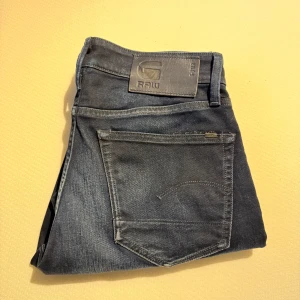 Mörkblå jeans från G-Star RAW - Snygga mörkblå jeans från G-Star RAW, modell 3301 Straight Tapered. Perfekta för en stilren look. Knappast använda då de är för små på mig, fråga inte om fler bilder eller mått och liknande broke ahh de ett par jeans damn köp eller ej liksom så enkelt de ingen raketforskning gng. Highkey unisex. Storlek ser ni på andra bilden.