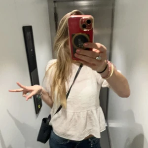 Vit blus - Säljer en söt vit blus med korta ärmar och en lätt volangdetalj vid nederkanten. Perfekt för en avslappnad och stilren look. Passar bra till jeans eller kjol.