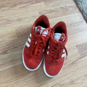 Adidas sneakers - Färgen är röd/orange, mest åt det orangea hållet. Väldigt sköna att gå i. 