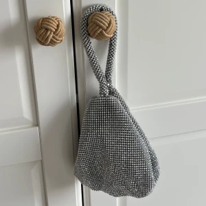 Glittrig axelväska - Snygg glittrig axelväska med ett unikt rutmönster. Perfekt för att ge din outfit en extra touch av glamour. Väskan har en enkel design med en bekväm axelrem.