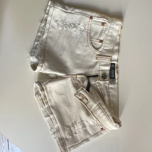 Vita jeansshorts  - Snygga vita jeansshorts från N3T JEANS med slitna detaljer och klassisk femficksdesign. Perfekta för sommardagar. De har en knappgylf och är lågmidjade.