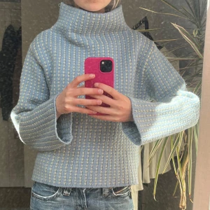 Blå stickad polotröja - Säljer en mysig blå stickad polotröja med ribbat mönster. Tröjan har en hög krage och långa ärmar, perfekt för kyligare dagar eller en sommarkväll.